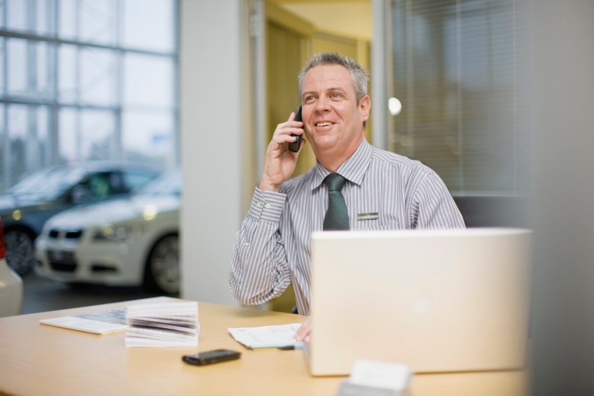 Car salesman on phone in showroom